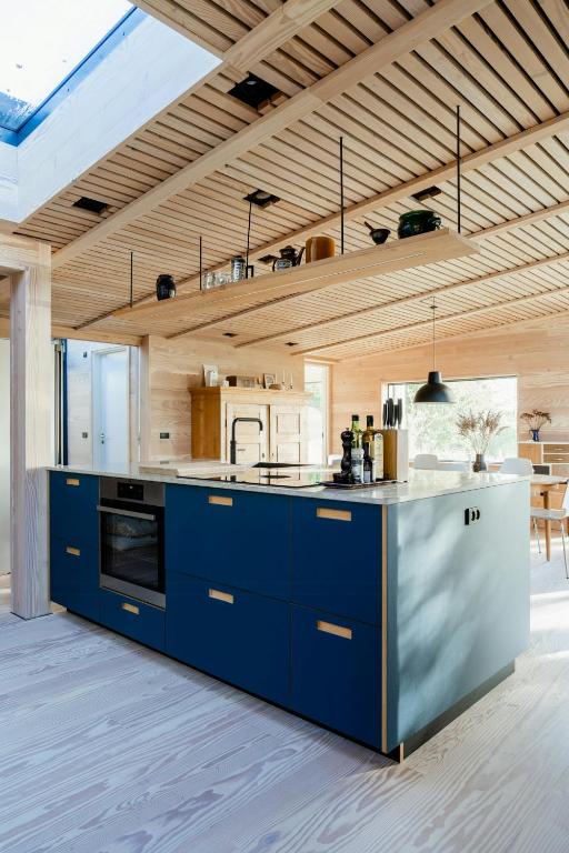 a large kitchen with blue cabinets and a counter at Feel The Nature Inside In Architect-Designed Gem in Nibe
