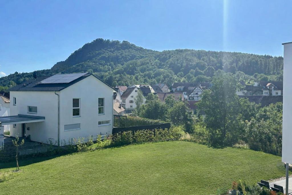 a white house on a hill with a green yard at Auszeit im Hegau Bodenseenahe Ferienwohnung in Engen