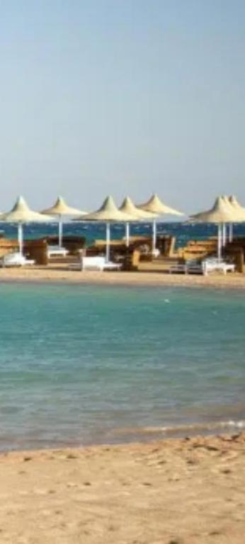 a beach with a group of umbrellas and the water at Private apartment beach resort in Hurghada