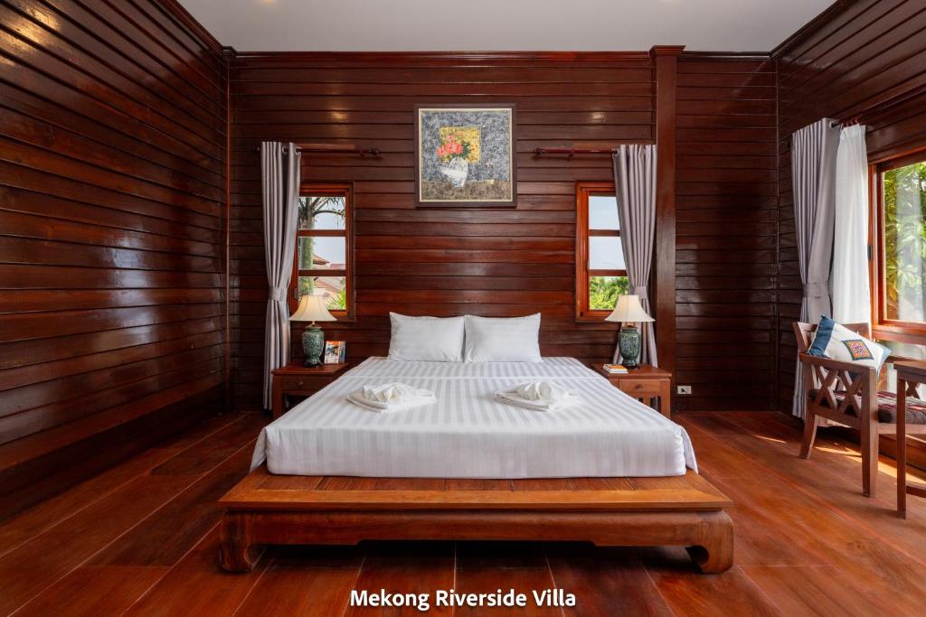 a bedroom with a bed with wooden walls and wooden floors at Mekong Riverside Villa in Vientiane
