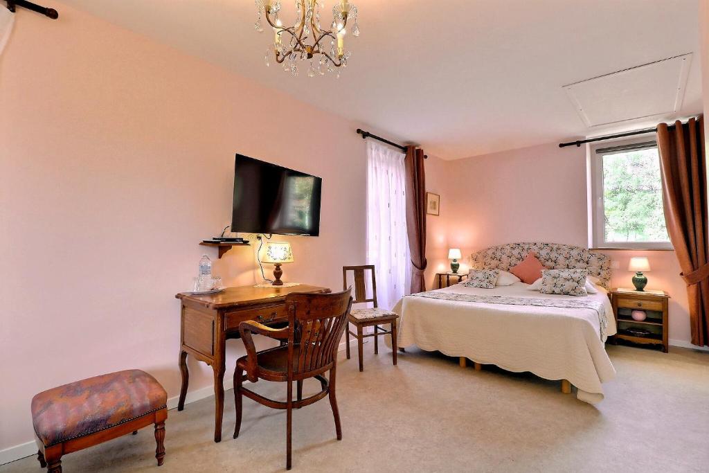 a bedroom with a bed and a desk and a bed and a window at Le Moulin du Bignon in Lassy