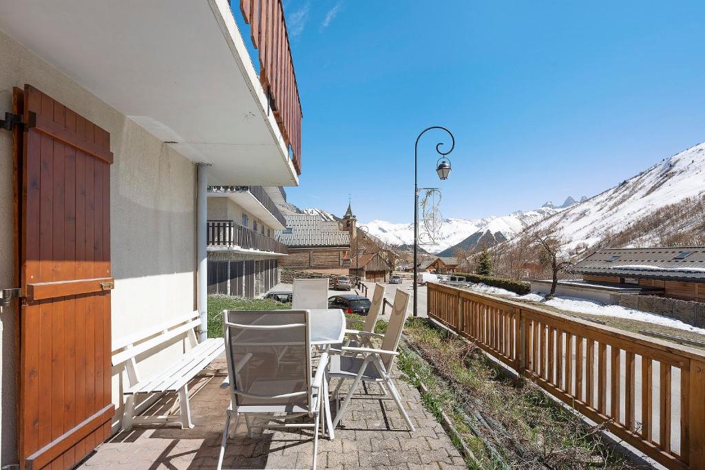 a porch with chairs and a table with snow covered mountains at Appartement St so in Saint-Sorlin-dʼArves