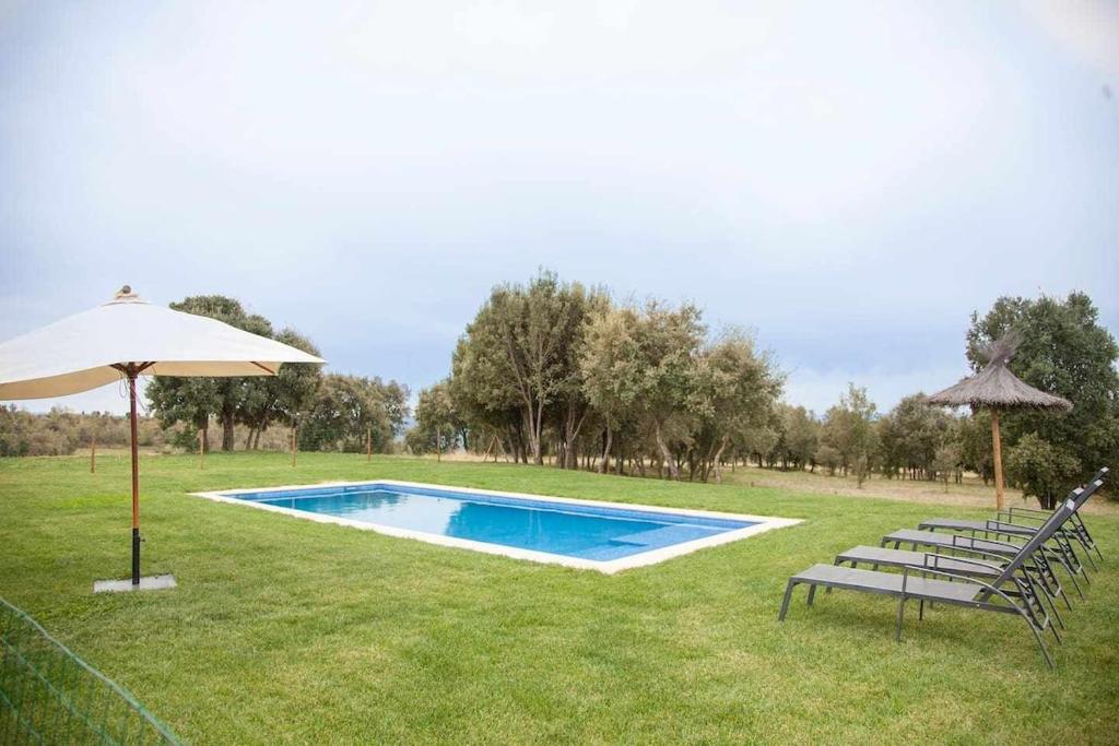 a swimming pool with two chairs and an umbrella at El Mas de Mateus in Sagás