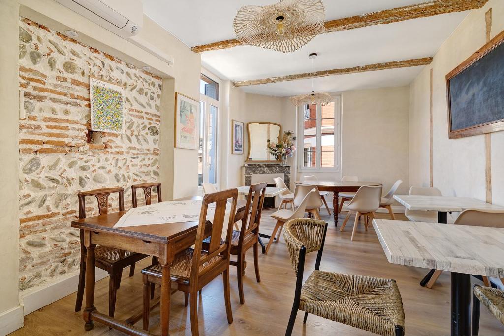 a dining room with tables and chairs and a brick wall at Appartement Graingalet in Carbonne