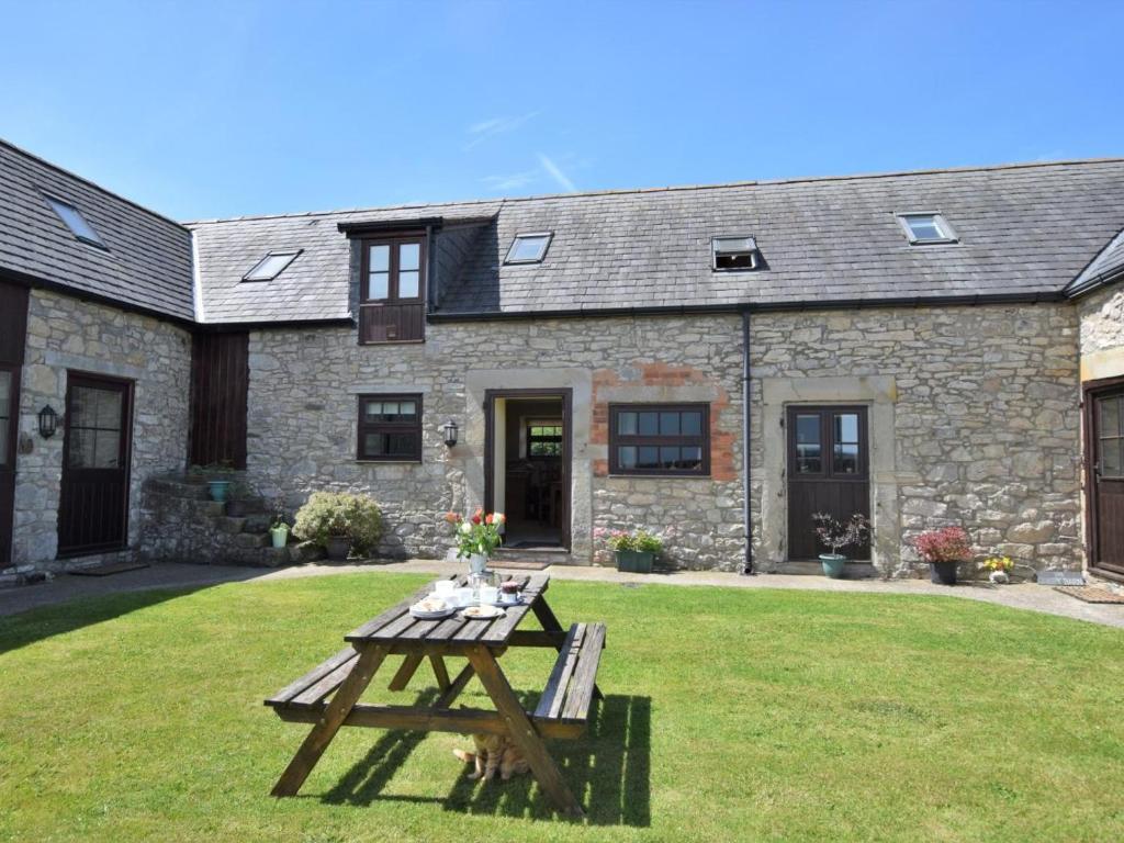a picnic table in front of a stone house at 2 Bed in Mold oc-41656 in Caerwys