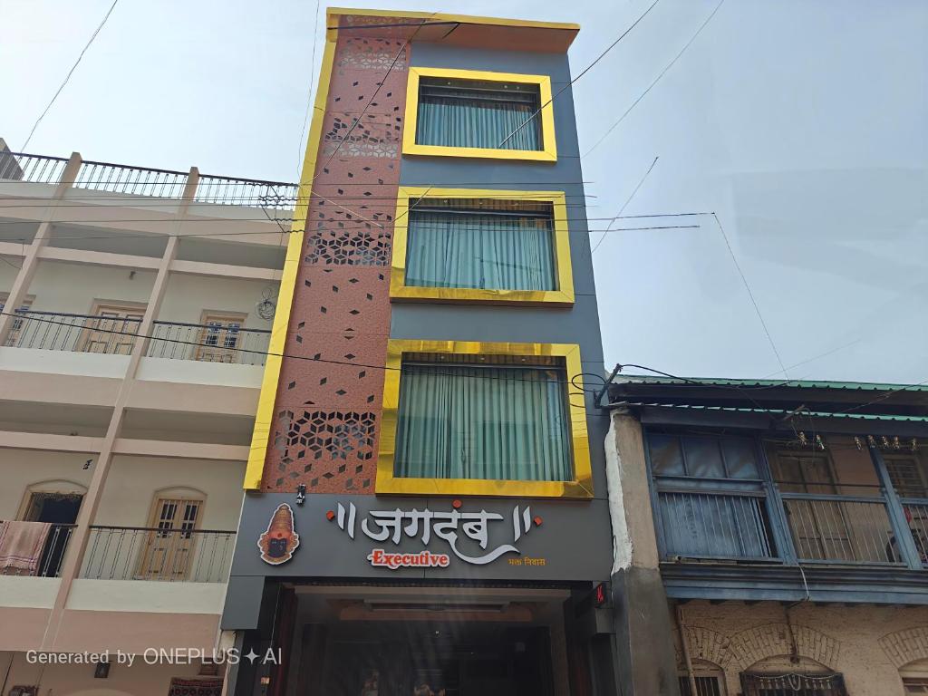 a tall building with a sign on the side of it at Hotel Jagdamb Kolhapur in Kolhapur