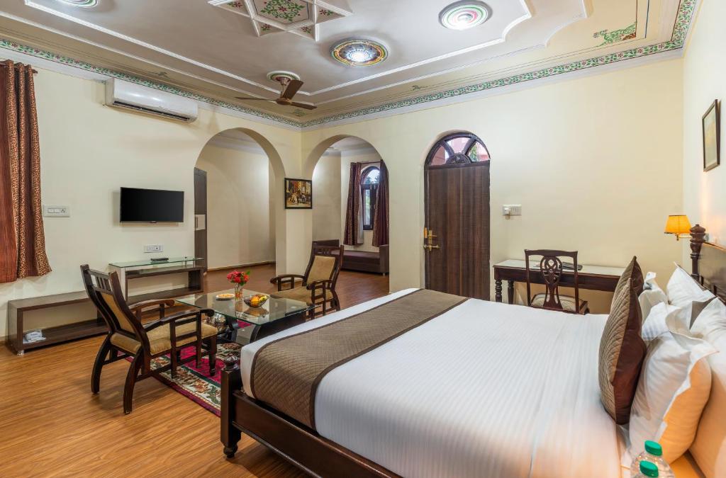 a hotel room with a bed and a table and chairs at Bijainagar Fort in Jāmb