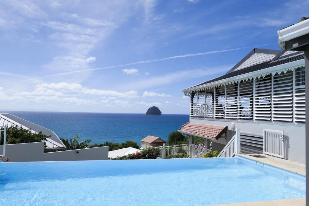 a villa with a swimming pool and a view of the ocean at Cœur de Diams in Le Diamant