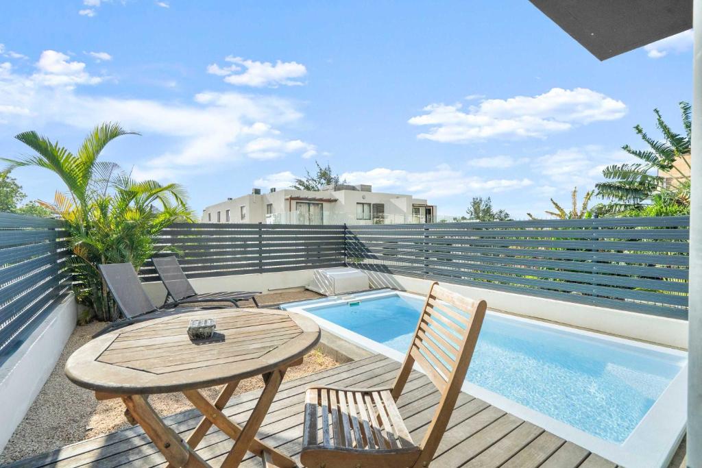 a patio with a table and chairs and a swimming pool at Golden Bloom - High-End Duplex w Private Pool in Rivière Noire