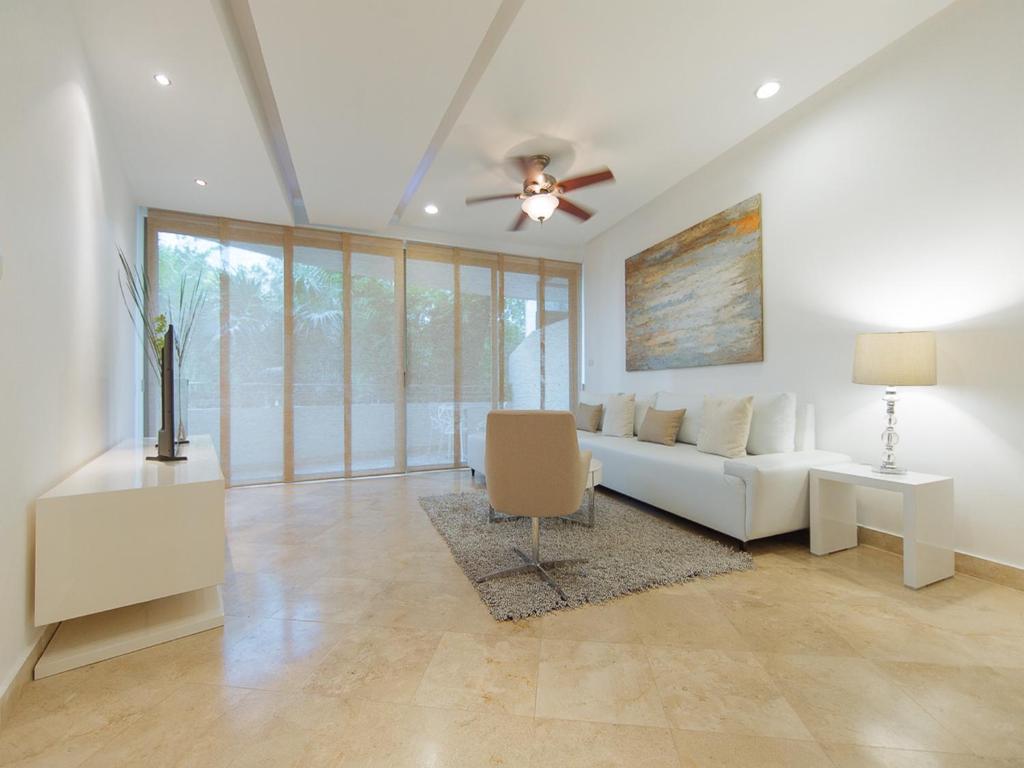 sala de estar con sofá blanco y ventilador de techo en Charming 2BR condo in quiet surroundings by Happy Address, en Playa del Carmen