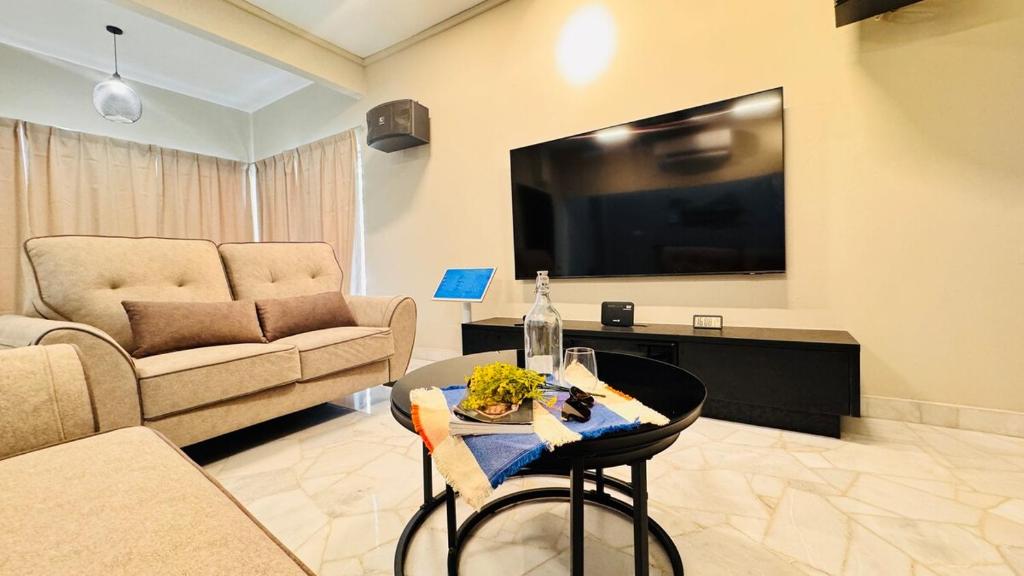 a living room with a couch and a table and a tv at uncommon homestay in Klang