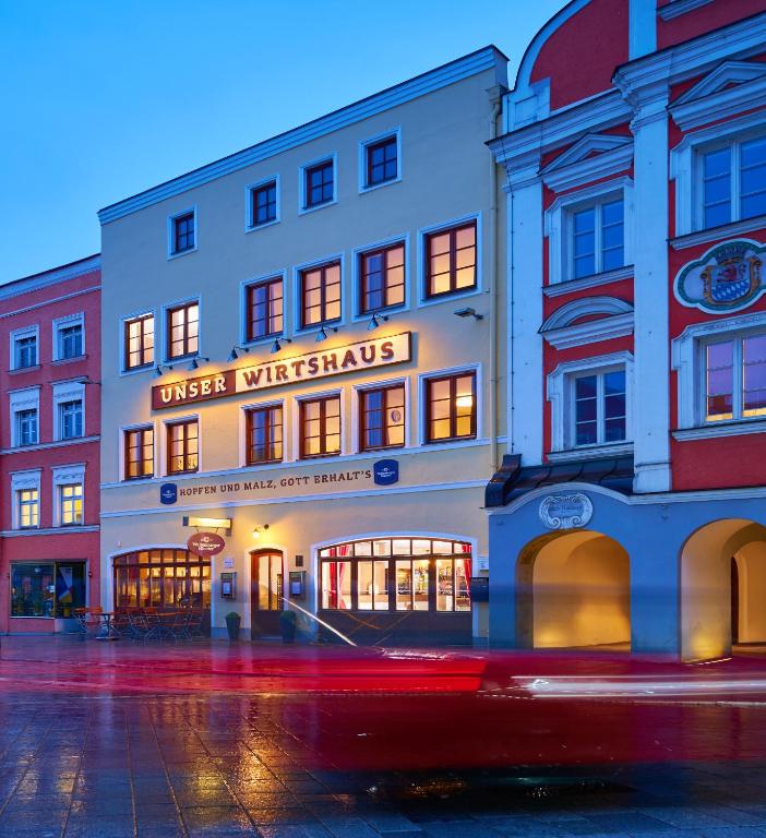 ein rotes Auto fährt an einem Gebäude auf einer Straße vorbei in der Unterkunft Unser Hotel in Eggenfelden