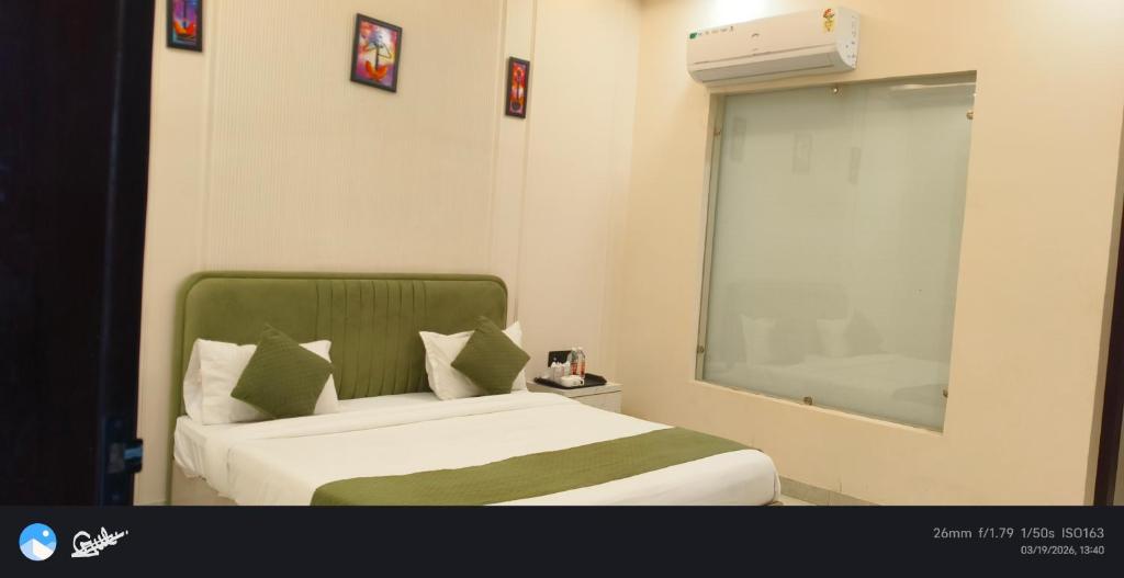 a bedroom with a bed with a green headboard and a window at The grand regency in Rāmpur