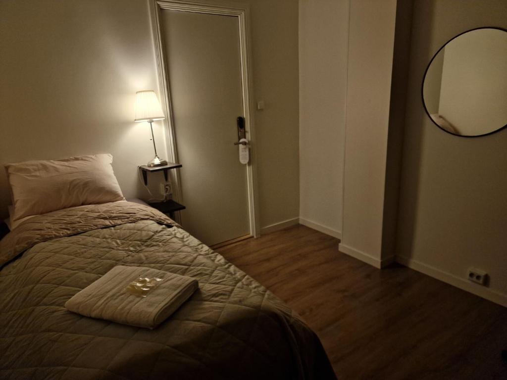 a bedroom with a bed with a mirror and a lamp at Järnvägshotellet Charlottenberg in Charlottenberg