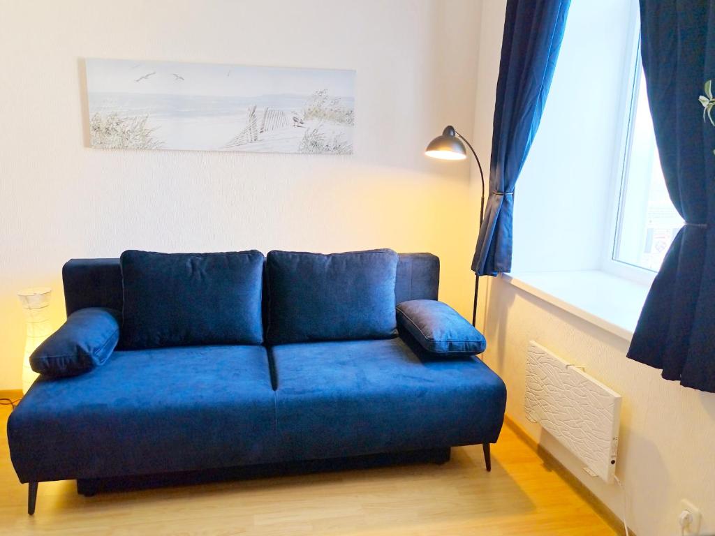 a blue couch sitting in a room with a window at Studio, Fireplace, Super location, Free Parking in Tallinn