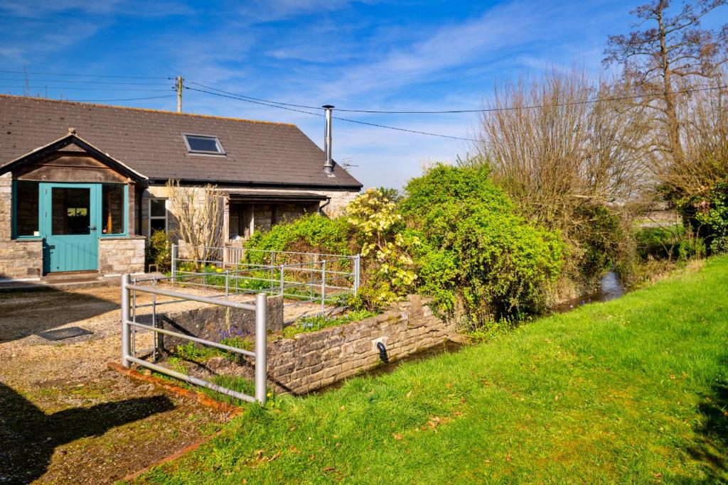 a house with a fence in front of a yard at Finest Retreats - Mill Barn By The Stream in West Lydford