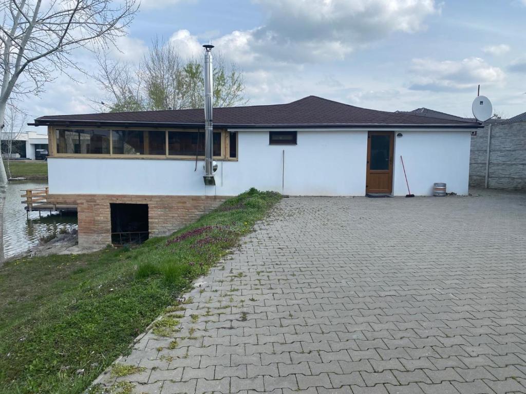 a white house with a brick driveway in front of it at MAX apartmán jazero in Trstice
