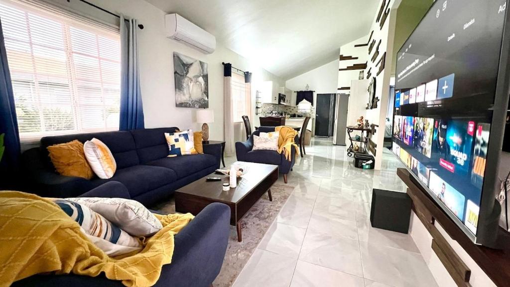 a living room with blue couches and a flat screen tv at Coral Cove Oasis in Discovery Bay