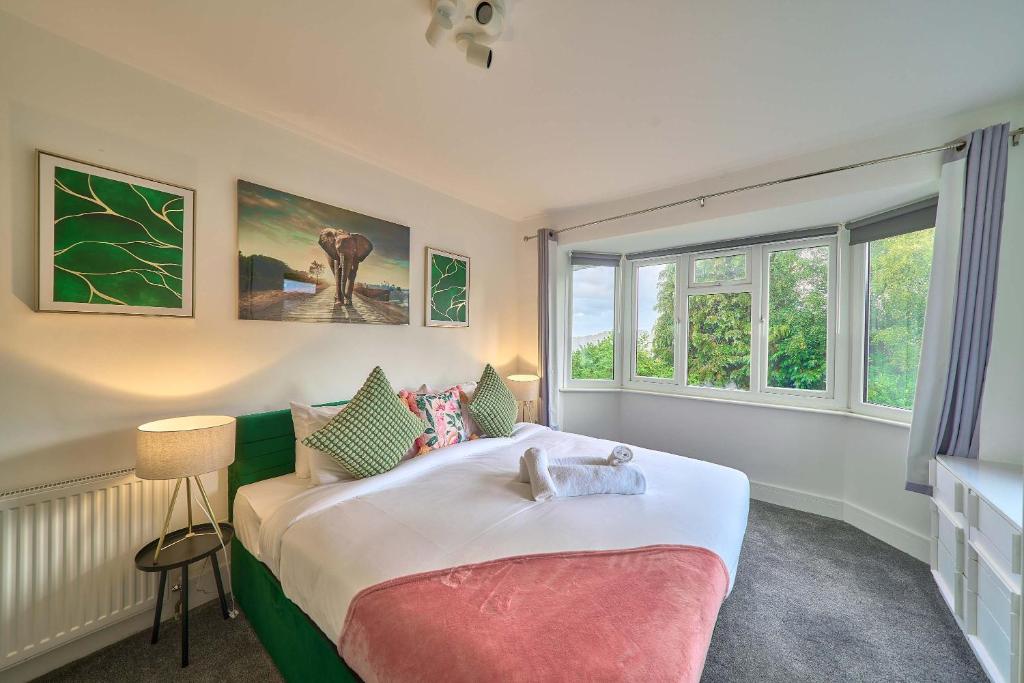 a bedroom with a large bed and two windows at Contractor Base 4BR Fast WiFi Parking High Wycombe in Buckinghamshire