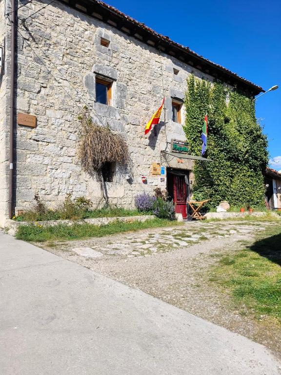 a stone building with a flag in front of it at Hotel Rural Papasol in Atapuerca