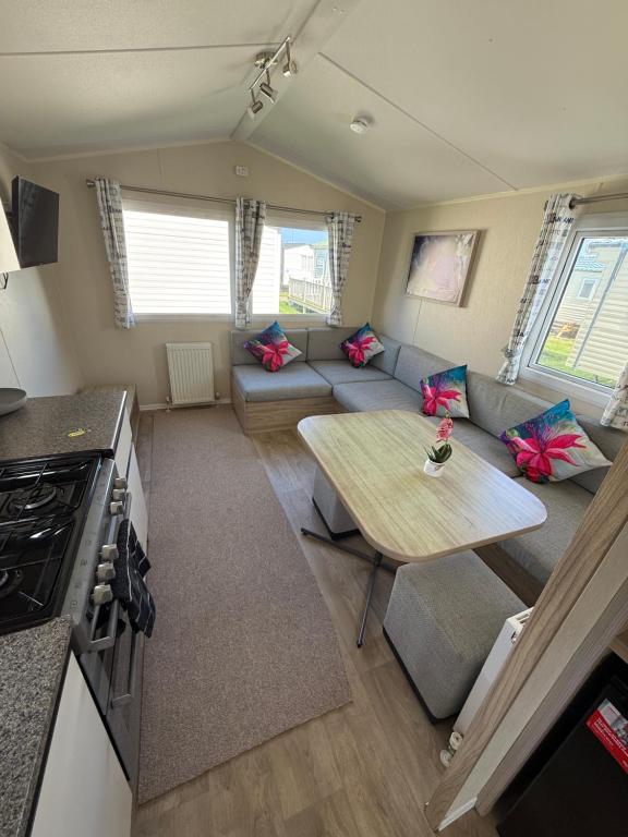 a living room with a couch and a table at Seaside Caravan in a Leisure Park with WiFi & Parking - 3 bedrooms in Meliden