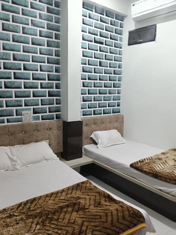 two beds in a room with a brick wall at Hotel Sadashiv in Godarpura