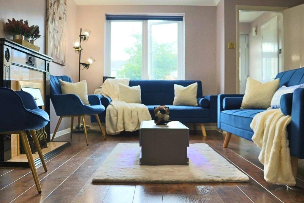 a living room with blue couches and a dog on a table at Luxury Heathrow Modern House with Parking & Fast WiFi in Northolt