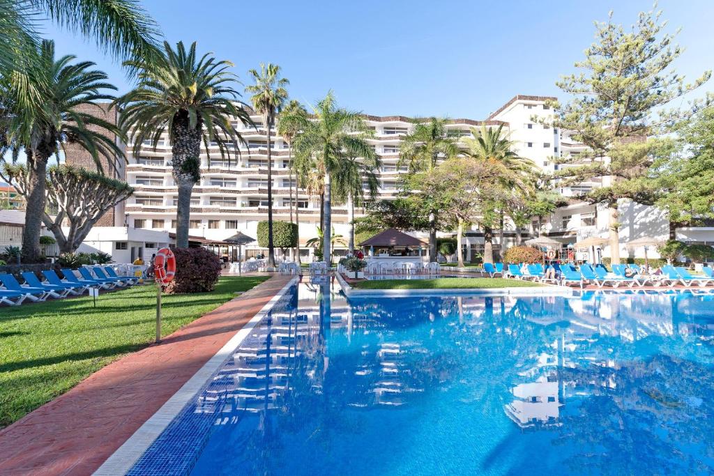 a large swimming pool with blue chairs and a building at Complejo BLUESEA Puerto Resort compuesto por Hotel Canarife y Bonanza Palace in Puerto de la Cruz