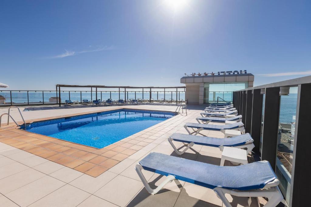 a row of lounge chairs next to a swimming pool at BLUESEA Calabahía in Cala del Moral