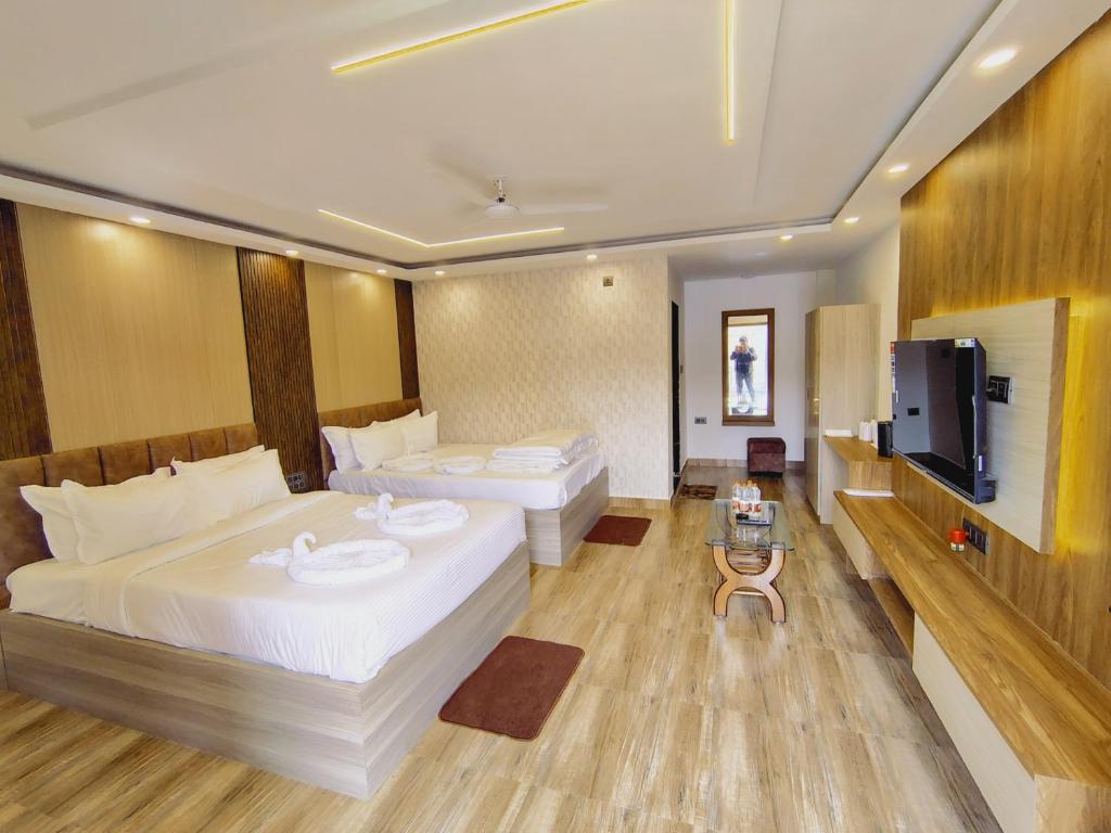 a hotel room with two beds and a flat screen tv at White Coastal Beach Resort in Mandarmoni