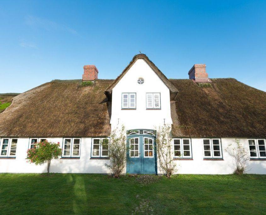 a large white house with a grass roof at Hansen-Hof-Wohnung-2 in Tinnum