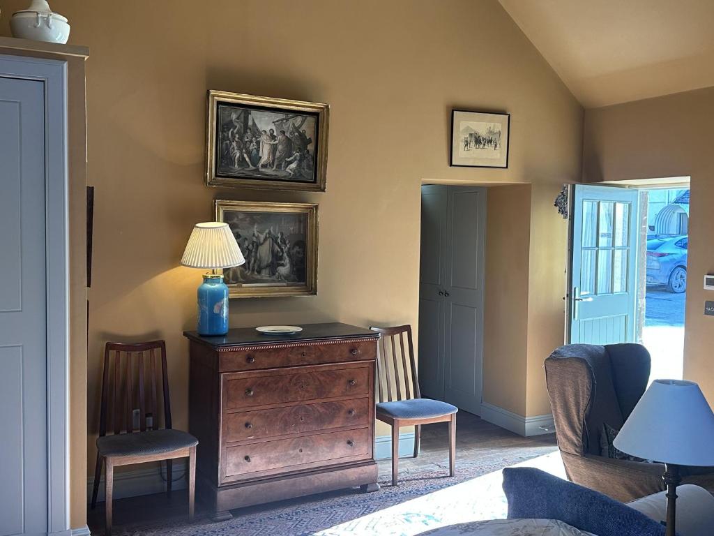 a room with a dresser with a lamp and two chairs at Barns Studio in Peebles