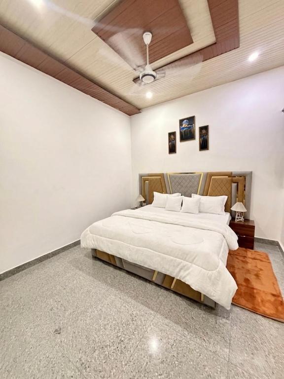 a bedroom with a large bed with white walls at Luxury Palm Stay in Jammu