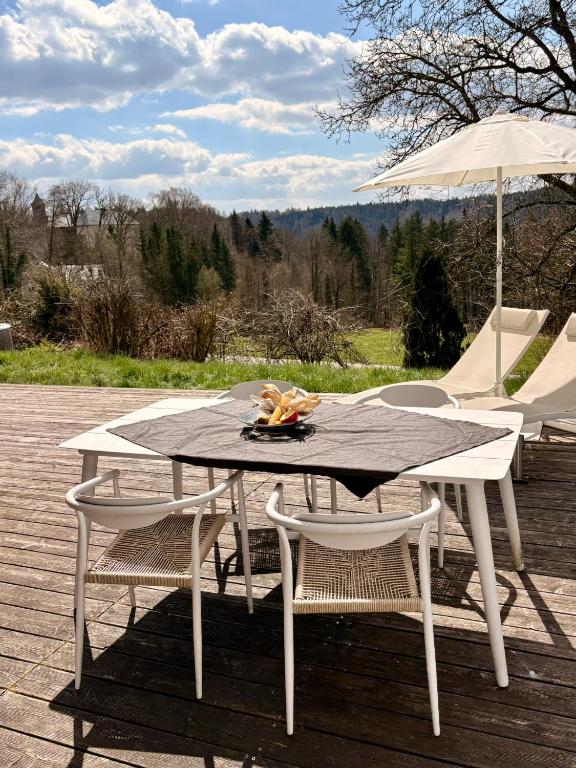 a picnic table with two chairs and an umbrella at Weitblick am Mangfalltal in Feldkirchen-Westerham