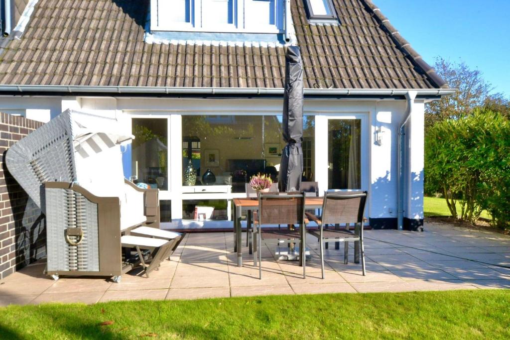 a patio with a table and chairs in front of a house at Syltstyle-12 in Tinnum