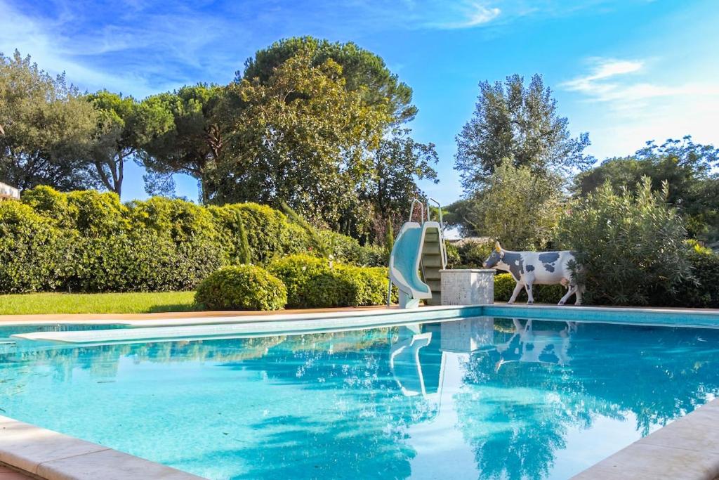a swimming pool with a cow statue next to a house at Villa Alberta With Reserved Beach Spot in Marina di Massa