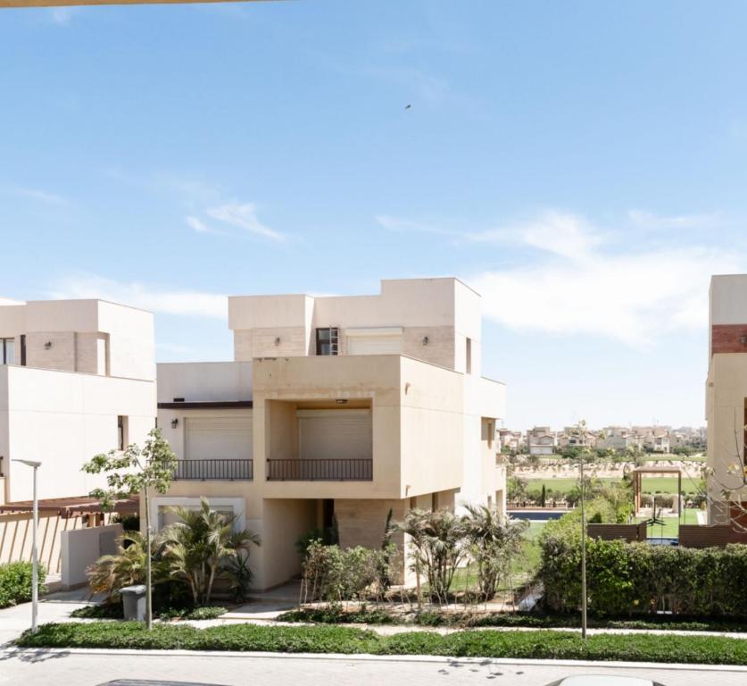 a large white building with palm trees in front of it at Marassi Stand alone luxury villa in El Alamein