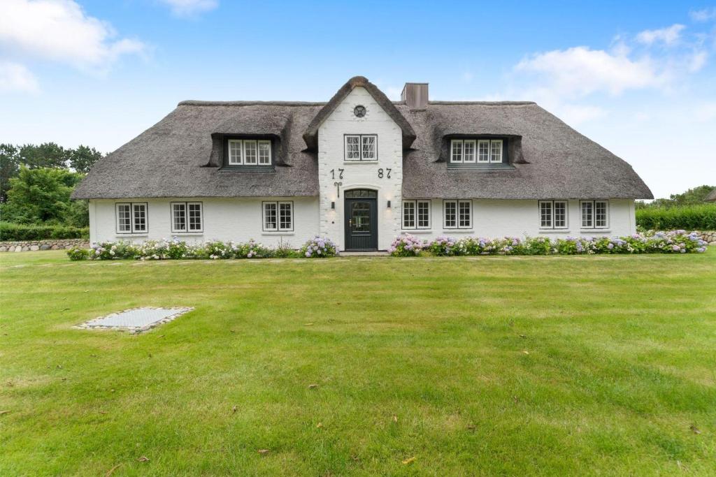 a large white house with a grass yard at Carolinenhof-2 in Tinnum