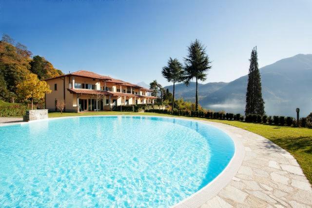 a large blue swimming pool in front of a house at Tremezzo Residence in Tremezzo