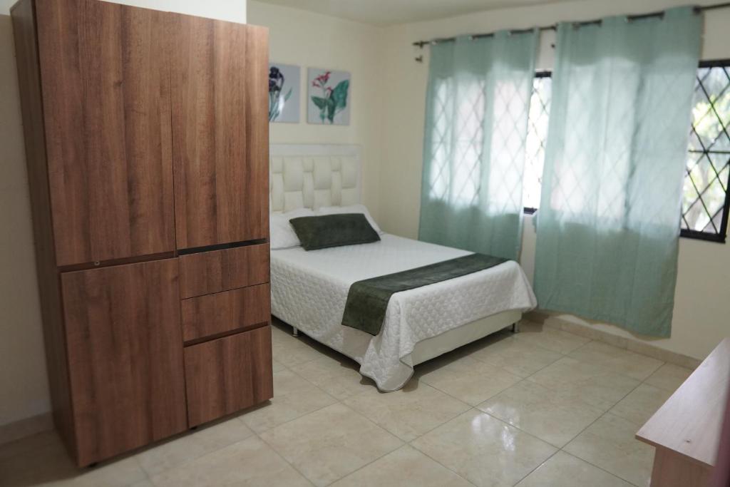 a bedroom with a bed and a wooden cabinet at Casa Esperanza in Cali