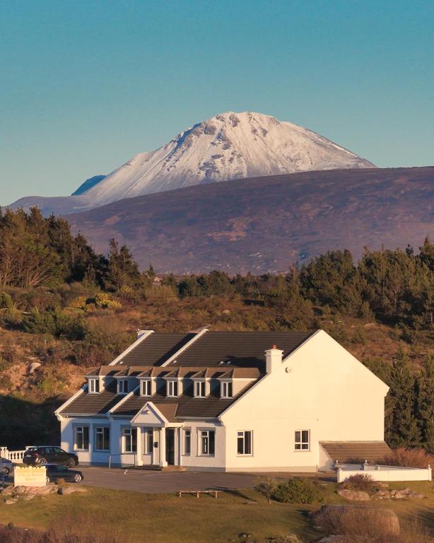 a house with a snow covered mountain in the background at Viking House Hotel Donegal in Kincasslagh