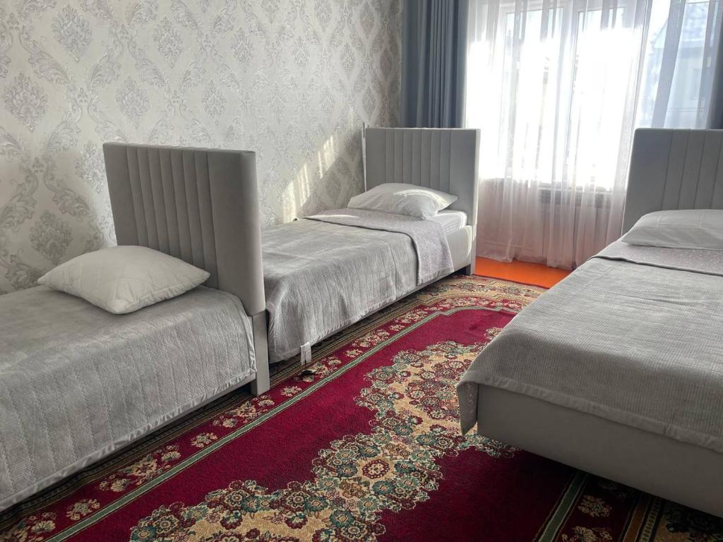 two beds sitting in a room with a rug at Hanbiike in Karakol