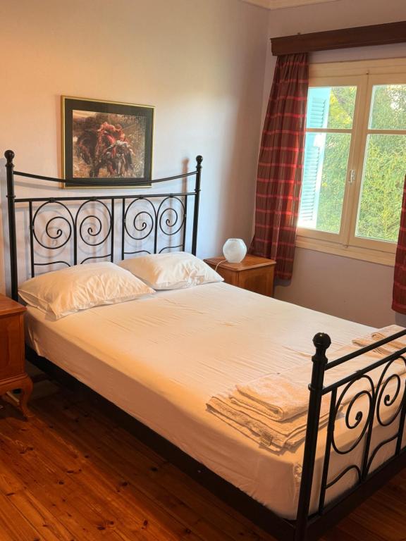 a bedroom with a bed with white sheets and a window at Philoxenia in Spata