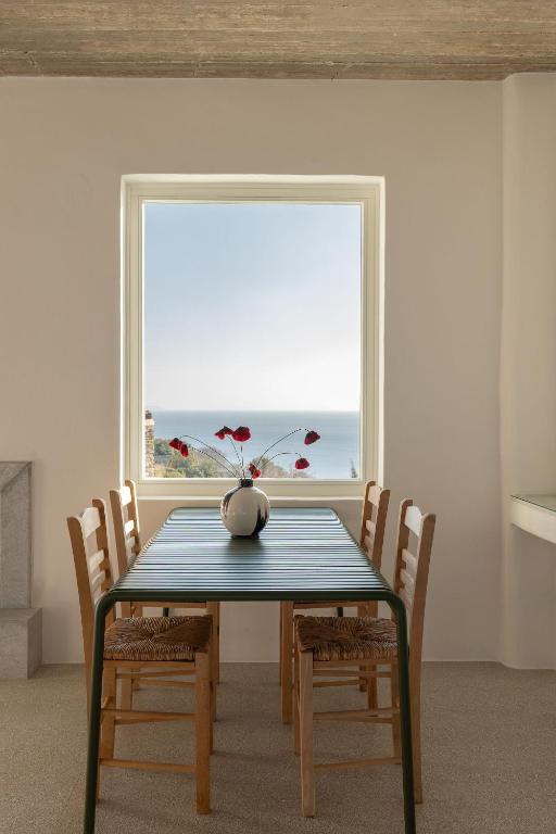 a dining room with a table and chairs and a window at Villa Petra in Andros