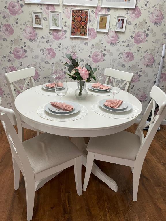a white dining room table and chairs with flowers on it at Dare apartments 2 in Giurgiu
