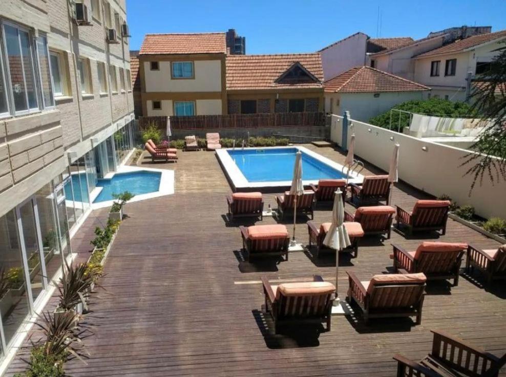a deck with chairs and a swimming pool at hotel Villa Gesell Spa in Villa Gesell