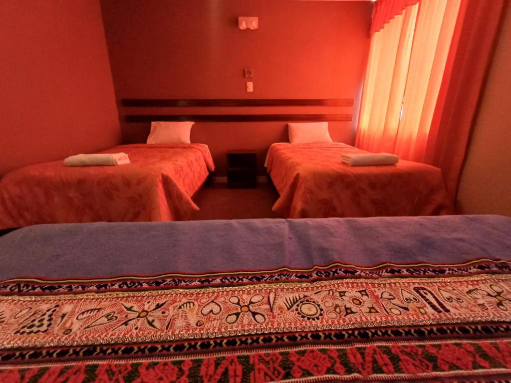 two beds in a room with red walls at Colca Terra in Chivay