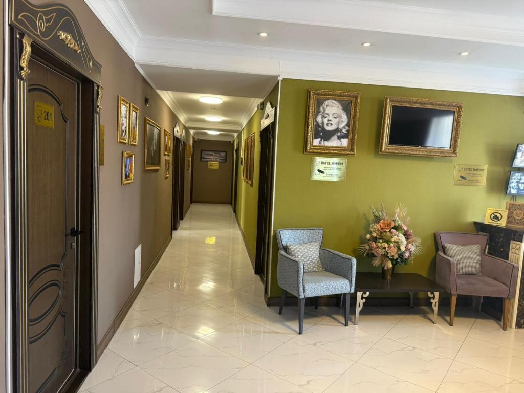 a hallway with green walls and chairs and a table at Monroe Hotel in Almaty
