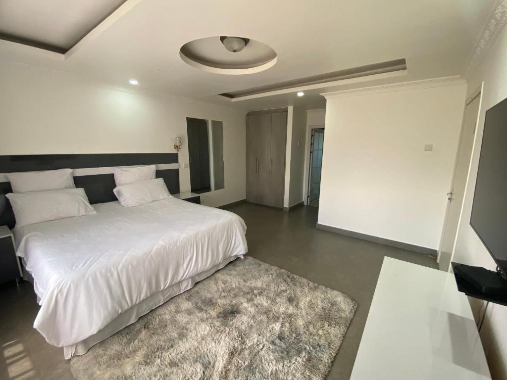a bedroom with a large white bed and a rug at The 'C' Apartments in Mansa