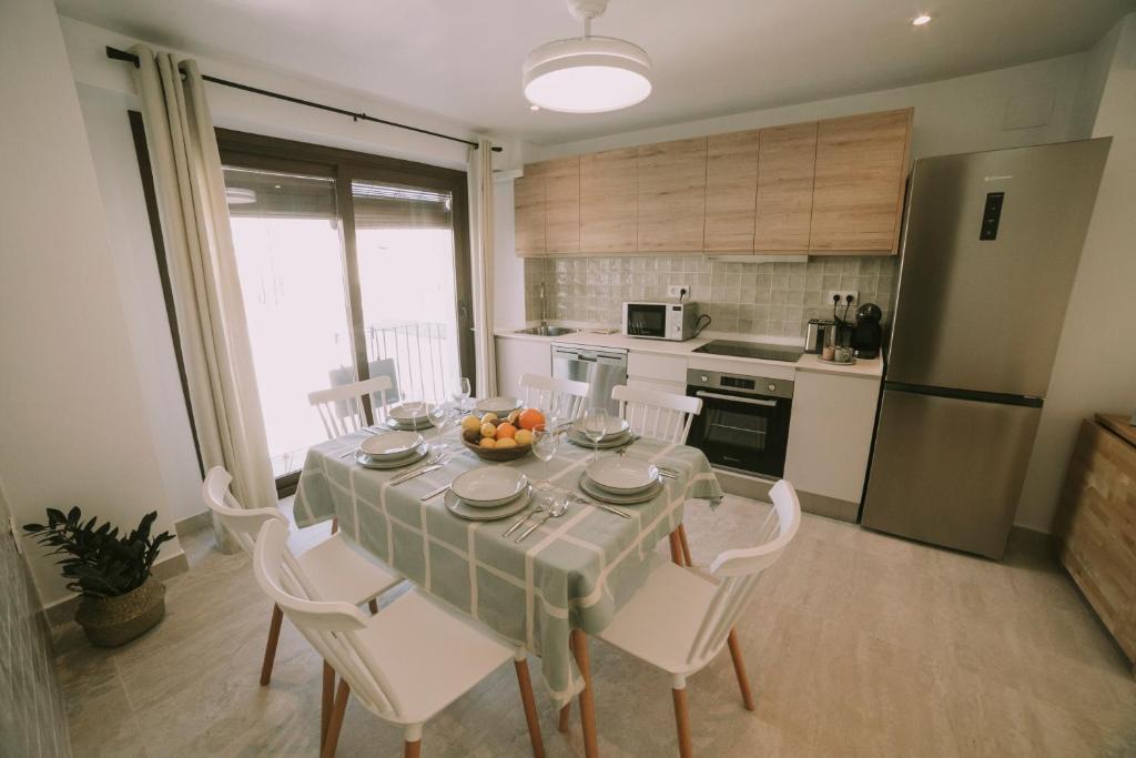 a kitchen with a table with white chairs and a kitchen with a refrigerator at Casa Aula Minerva Lumen 3 Dormitorios in Almedinilla